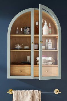 a bathroom with blue walls and wooden shelves filled with personal care items, such as toiletries and hand towels