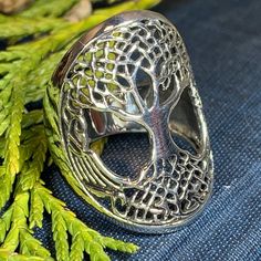 a ring with a tree on it sitting next to some green leaves and rocks in the background