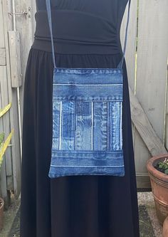 a woman wearing a black dress with a blue jean purse hanging from it's back