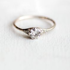 a white gold ring with two diamonds on it, sitting on top of a table