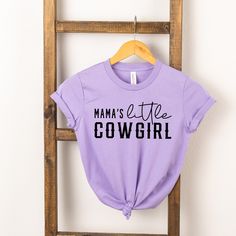 Looking for a cute tee for your kids? We have the perfect Mama's Little Cowgirl graphic tee addition to their closet! Purple Graphic Tee With Funny Print, Fun Purple T-shirt With Funny Print, Purple Cotton T-shirt With Letter Print, Cute Purple Top With Graphic Print, Cute Purple Short Sleeve T-shirt, Trendy Purple Slogan T-shirt, Spring Lavender Letter Print Top, Fun Purple Cotton Tops, Cute Lavender Cotton Top