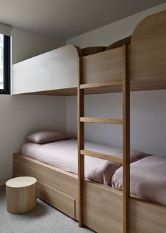 two bunk beds in a room with no one on the bed and an ottoman next to them