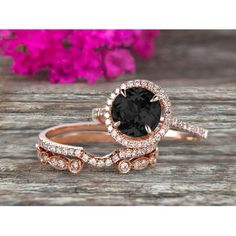 a black and white diamond engagement ring set on top of a wooden table with flowers in the background