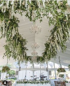 the ceiling is covered with greenery and chandeliers for an elegant wedding reception