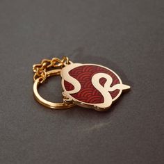 a red and gold keychain with the letter s on it's side