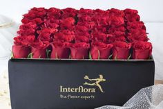 a black box filled with red roses on top of a table