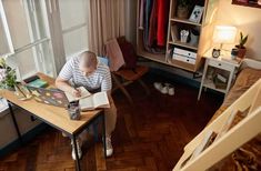 a man sitting at a desk in front of a window with an open book on it