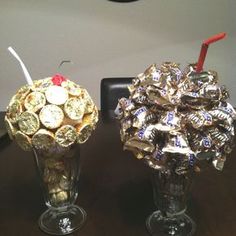 two vases filled with gold and silver foil covered chocolate coins sitting on top of a wooden table