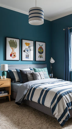 a bedroom with blue walls, striped bedding and two pictures on the wall above the bed