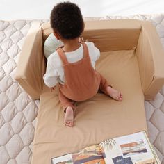 a small child sitting on top of a bed next to an open book