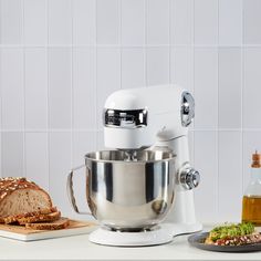 a kitchen mixer sitting on top of a counter next to bread