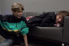 two boys are laying on the couch and laughing