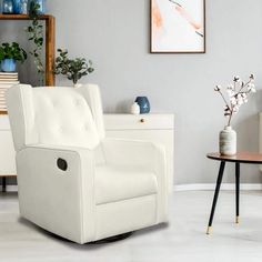 a white chair sitting in a living room next to a table with vases on it