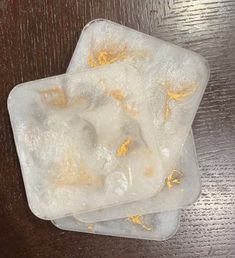 two pieces of ice sitting on top of a wooden table covered in yellow and white stuff