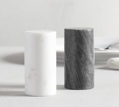 two marble vases sitting next to each other on a white tablecloth covered table