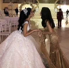 two women dressed in gowns standing next to each other at a formal event together