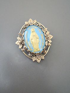 "Vintage Jewelry - Vintage Brass - Blue Brooch - Mother Mary Jewelry - Catholic Brooch - Religious Jewelry - handmade jewelry This is such a pretty brooch! Vintage brass setting embellished with a vintage light blue and gold vintage cameo of the Mother Mary. Exquisite detail with a rich patina on the brass. This is a real special piece. Chloe says, \"Wear it and feel fabulous!\" The pendant is 1 1/4\" long Thanks for visiting Chloe's" Blue Brooch Pin For Gift, Blue Brooch Pins As A Gift, Blue Brooch Pin As Gift, Blue Brooch Pins For Gift, Vintage Blue Enamel Pin Gift, Blue Brooch Lapel Pin As Gift, Antique Blue Collectible Brooches, Antique Handmade Blue Brooches, Mary Jewelry