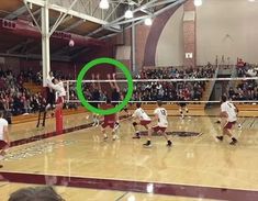 a group of people playing volleyball on a court with an object in the foreground