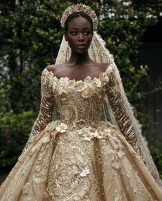 a woman in a gold wedding gown with flowers on the skirt and headpieces