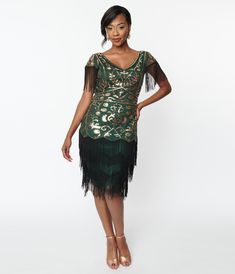 A playful vintage inspired flapper dress featuring emerald green mesh that dances with gold sequins over emerald green lining. Outfitted with black fringe dancing from the cap sleeves and tiered skirt while complete with a mid side zipper.Available in sizes S-3X while supplies last. Fringe Flapper Dress, Uv Clothing, 1920s Outfits, Flapper Costume, Black Fringe, Green Outfit, Gold Sequins, Vintage Branding, Gold Sequin