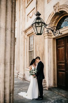 a bride and groom standing in front of an old building