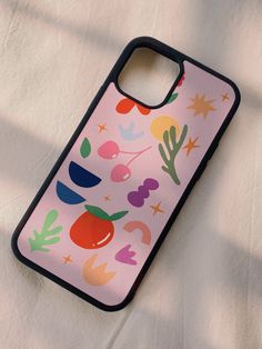 a pink phone case with colorful fruit and stars on it, sitting on a white sheet