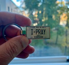 a person holding up a tiny keychain with the word 1 - pray printed on it