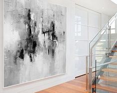 an abstract painting hangs on the wall next to a stair case in a modern home