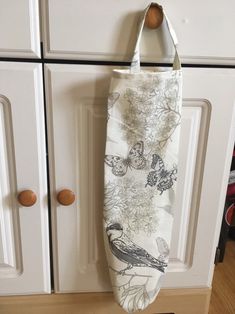 a bag hanging from the side of a white cabinet with flowers and birds on it