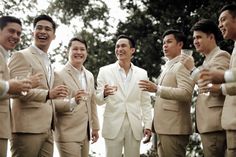 a group of men standing next to each other holding wine glasses in their hands and smiling at the camera