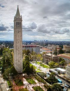 a large clock tower towering over a city filled with tall buildings and green park like areas