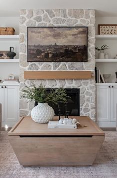 a living room with a stone fireplace and large painting on the wall over the mantle