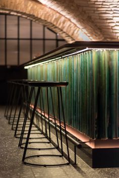 three bar stools sitting next to each other in front of a brick wall and ceiling