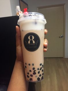 a person holding up a drink in front of the camera with black spots on it