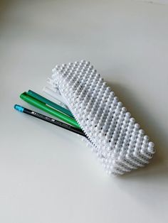 three pencils are sitting on top of a white object that looks like a toothbrush holder