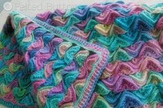 a colorful crocheted blanket is laying on the floor with it's edges folded down