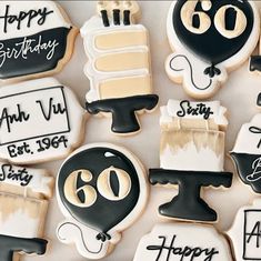 decorated cookies with black and white icing are arranged on a table top, including an 80th birthday cake