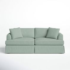 a light green couch with two pillows on the back and one arm folded over it