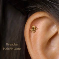 a close up of a person's ear with a small gold flower on it