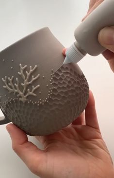 a person is holding a cup that has been decorated with white corals on it