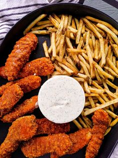 fried chicken and french fries in a pan with ranch dressing