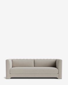 a white couch sitting on top of a floor next to a gray wall with a light colored