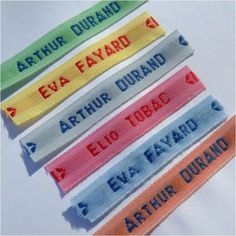 four different colored name tags on white paper with blue, red, yellow and green lettering