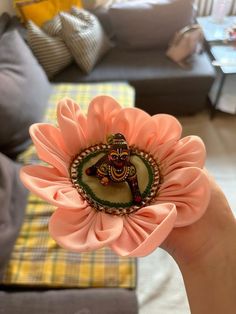 a person holding a pink flower with a statue on it's center in front of a couch