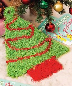 a christmas tree made out of green grass next to a book and other holiday decorations