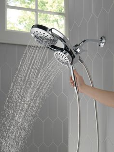 a person is holding the shower head in their hand