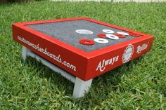 a red and white game table sitting in the middle of some grass with buttons on it