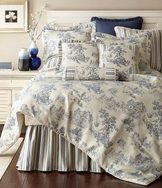 a bed with blue and white comforters, pillows and blankets on top of it