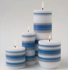 four candles with blue and white stripes are stacked on top of each other in front of a white background