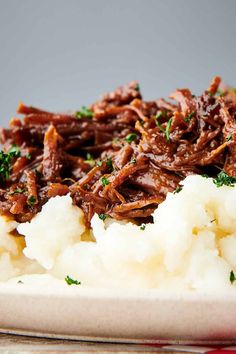 shredded beef and mashed potatoes on a plate with parsley garnishes